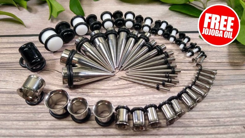 May include: A set of 20 stainless steel ear gauges and plugs, including a variety of sizes and styles, including tapers and tunnels. The set also includes a few pairs of black and white acrylic plugs. Free jojoba oil is included.