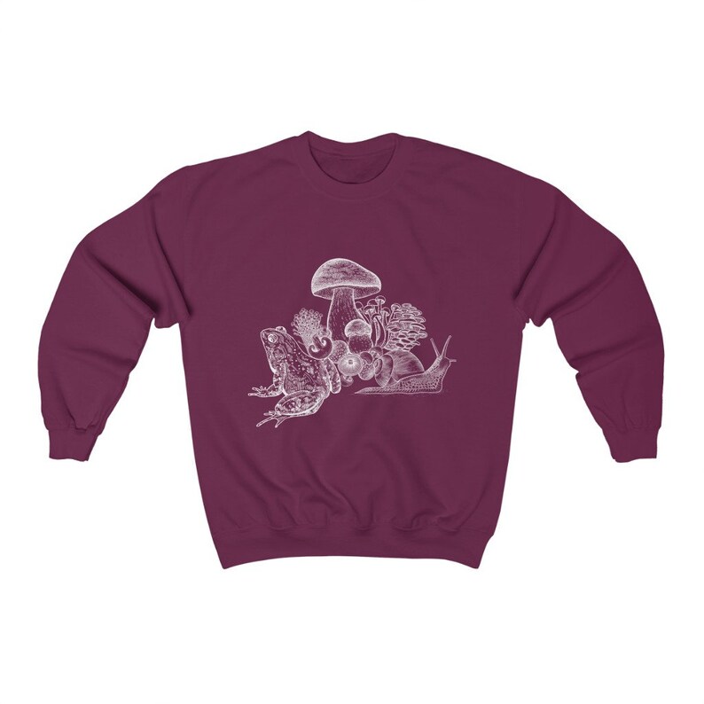 May include: A maroon sweatshirt with a white graphic of a frog, snail, and mushrooms.