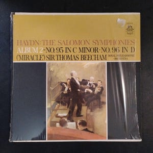 May include: A vinyl record album featuring Haydn's The Salomon Symphonies, Album 2, with Sir Thomas Beecham and the Royal Philharmonic Orchestra. The cover has a yellow top with text and a painting of an orchestra.
