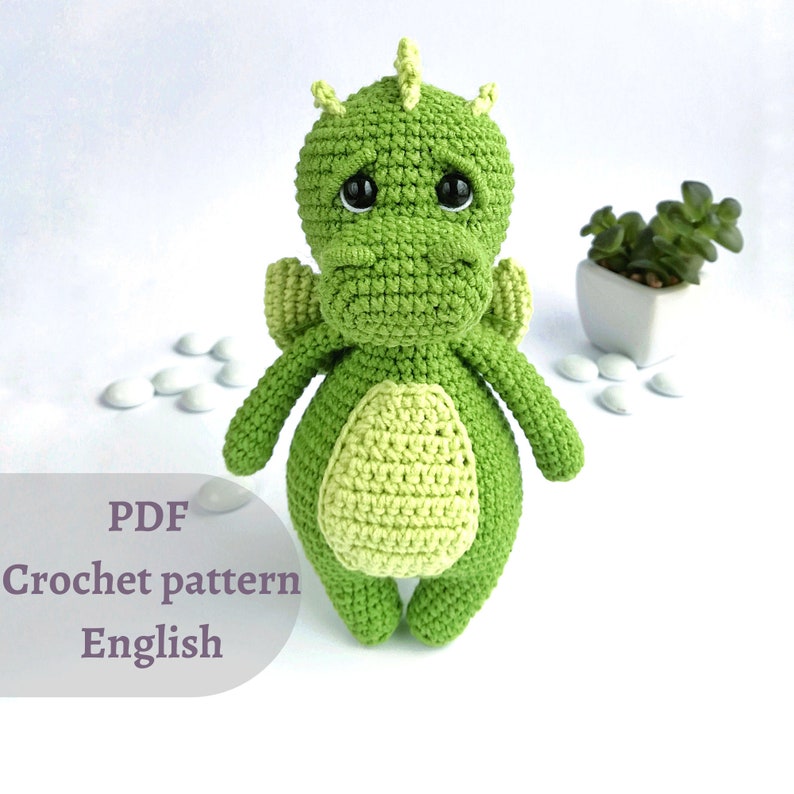 May include: A crochet pattern for a green dragon amigurumi toy. The pattern is in English and is available as a PDF download.