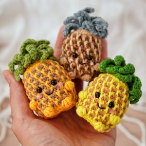 May include: Three crocheted pineapple plushies with smiling faces. The pineapples are yellow, brown, and green.