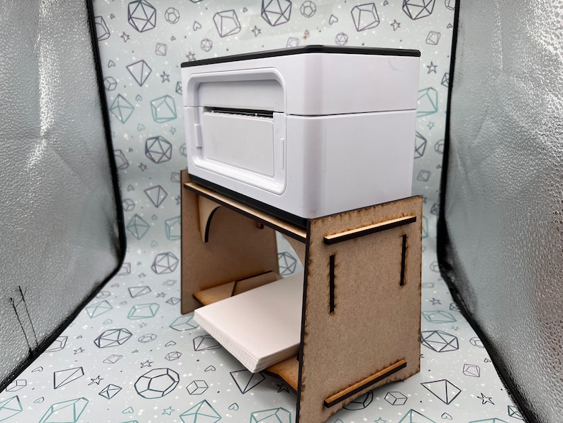 May include: A white printer sits on a wooden stand with a shelf. The stand is made of light brown wood and has a simple design.