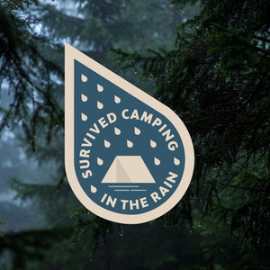 Puede incluir: Una pegatina de camping azul y blanca con el texto "Survived Camping in the Rain" y un icono de tienda de campaña. La pegatina tiene forma de gota de lluvia con gotas de lluvia alrededor del texto.