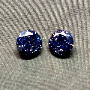 May include: A pair of round, blue glitter earrings. The earrings are a dark blue colour with silver glitter embedded in the resin.