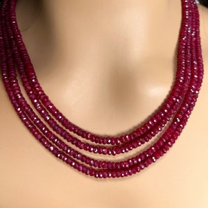 May include: A multi-strand necklace made of deep red ruby beads. The necklace is made of faceted beads and has a simple design.