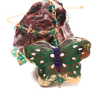 May include: A gold chain necklace with green glass beads and a green and gold butterfly pendant.