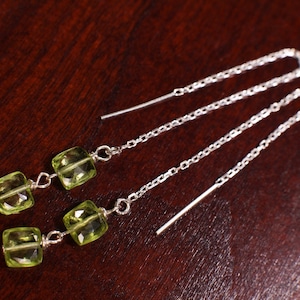 Puede incluir: Un par de pendientes de cadena de plata con dos piedras preciosas cuadradas verdes en cada pendiente.