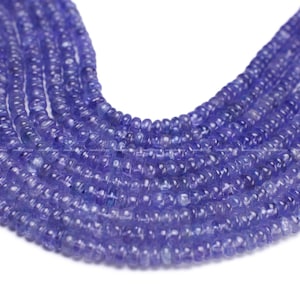 May include: A strand of blue gemstone beads, likely Tanzanite, with a smooth, rounded shape. The beads are strung together to create a long necklace or bracelet.