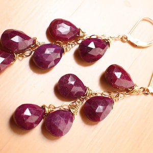 May include: A pair of dangle earrings with a gold chain and multiple ruby-coloured gemstone drops.