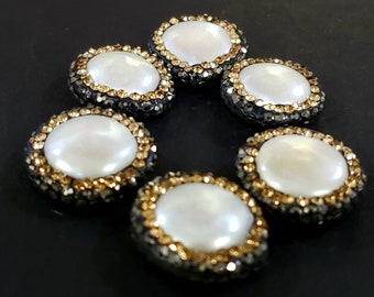 May include: Six round pearl-like buttons with a gold and black rhinestone border.