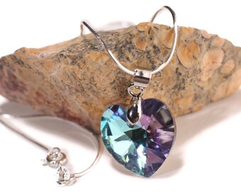 May include: A silver chain necklace with a heart-shaped pendant. The pendant is made of clear crystal with a blue and purple iridescent finish.