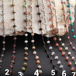 May include: Ten strands of beaded necklaces with black chain links. The beads are various colors and materials, including turquoise, pink, white, and black.