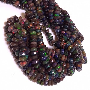 May include: A strand of dark iridescent opal beads, faceted and with a teardrop shape. The beads are strung on a clear thread and are approximately 4mm in diameter.