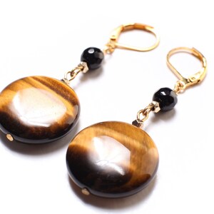 May include: Gold earrings with tiger's eye stone and black beads.
