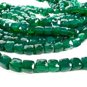 May include: A strand of green gemstone beads, each bead is faceted and has a square shape.