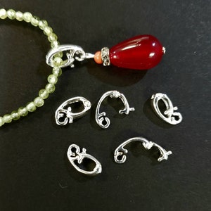 May include: A red gemstone pendant with a silver clasp and five silver clasps for a necklace or bracelet.