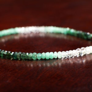 Könnte beinhalten: Ein grünes und weißes Ombre-Edelstein-Armband mit einem silbernen Verschluss und einem kleinen grünen Edelstein-Anhänger.
