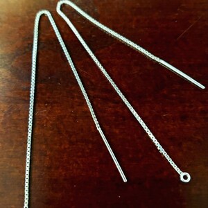 May include: Three silver chain earring extenders with a loop at the end of each chain.