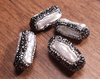 May include: Four white baroque pearl beads with black rhinestone accents. Each bead is approximately 2 inches long.