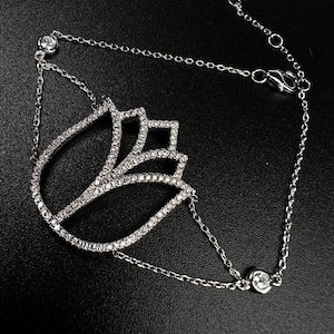 May include: A silver chain bracelet with a lotus flower design. The flower is made of small clear stones.