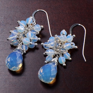 May include: A pair of silver dangle earrings with teardrop-shaped opal stones and clusters of smaller opal beads.