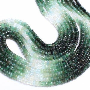 May include: A strand of green gemstone beads, with a gradient of color from light to dark green. The beads are faceted and have a round shape.