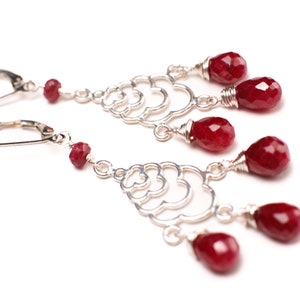 Peut inclure: Une paire de boucles d'oreilles pendantes en argent avec des gouttes de pierres précieuses rouges. Les boucles d'oreilles présentent un design délicat et complexe avec plusieurs couches d'argent.