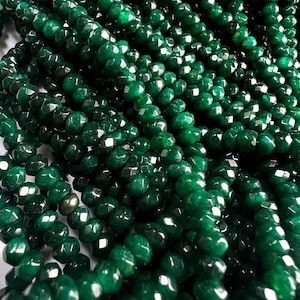 May include: A strand of dark green faceted gemstone beads. The beads are round and have a smooth, polished finish.