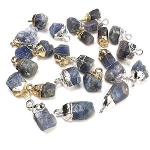 Könnte beinhalten: Eine Sammlung von 18 rohen blauen Saphir-Anhängern mit goldenen und silbernen Akzenten. Jeder Anhänger zeigt einen einzigartigen, rohen Saphir-Stein mit einer goldenen oder silbernen Öse für eine einfache Anbringung an Schmuck.