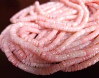 Pode incluir: Um fio de contas de opala rosa, cada conta é pequena, plana, de forma oval com uma borda ligeiramente irregular.