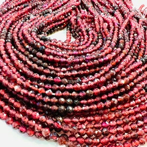 May include: A strand of deep red faceted garnet beads. The beads are round and have a smooth, polished finish.