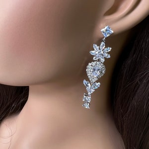 May include: Silver dangle earrings with clear crystal stones in a floral design.