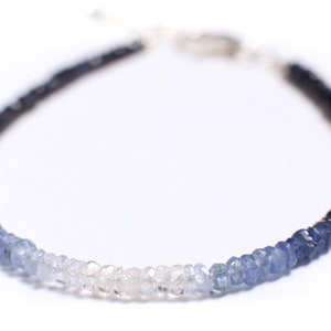 Könnte beinhalten: Ein zartes Ombre-Armband aus facettierten Saphirperlen. Die Perlen wechseln von Dunkelblau zu Hellblau und dann zu Klar.