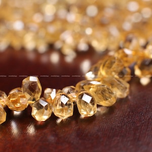 May include: A strand of faceted, golden citrine beads. The beads are arranged in a circular pattern and have a smooth, polished finish.