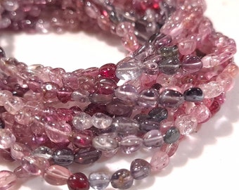 May include: A strand of pink, purple, and green gemstone beads. The beads are oval shaped and have a smooth, polished finish.