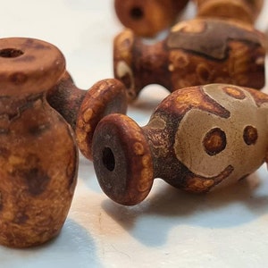 May include: A collection of brown and white agate beads with a mottled pattern. The beads are round and have a smooth, polished surface.