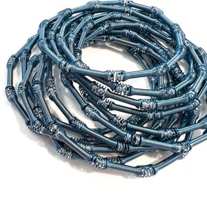 May include: A close-up of a coil of blue metal wire, resembling a spring, with a silver sheen. The wire is coiled into a circular shape, creating a decorative and unique design.