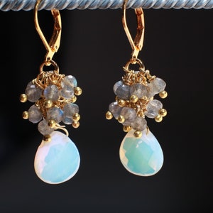 May include: Gold dangle earrings with a cluster of gray labradorite stones and a teardrop-shaped opal gemstone.
