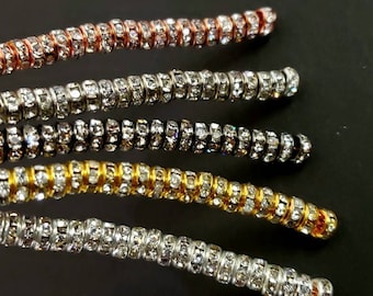 May include: Five strands of rhinestone trim in different colors, including silver, gold, black, rose gold, and white. Each strand is made of small, round rhinestones set in a metal wire.
