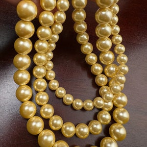 May include: A strand of multiple rows of golden yellow pearls. The pearls are large and round, and the strand is long enough to be worn as a necklace.