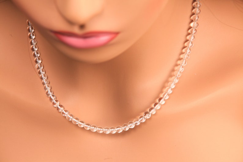 May include: A clear crystal beaded necklace on a mannequin.