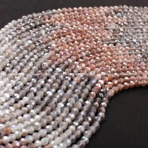 May include: Close-up of multiple strands of faceted beads in varying tones of grey, tan, and brown. The beads have a reflective surface, possibly crystal or gemstone. The beads are strung together, ideal for jewellery making.
