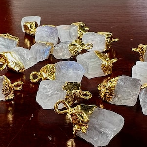 May include: A group of white crystal charms with gold accents. The charms are irregular in shape and have a rough, natural texture. They are perfect for adding a touch of sparkle and natural beauty to jewelry projects.