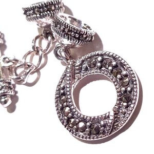 May include: Silver tone toggle clasp with a round, open circle design. The circle is decorated with small, black marcasite stones.