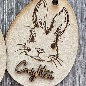 May include: Wooden Easter egg ornament with a laser-engraved bunny rabbit design and the name "Creighton" on the bottom.