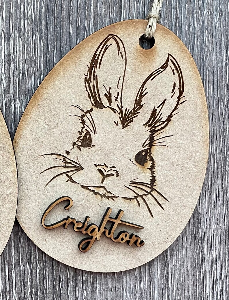 May include: Wooden Easter egg ornament with a laser-engraved bunny rabbit design and the name "Creighton" on the bottom.