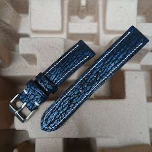 May include: Two navy blue watch straps with a textured finish and white stitching. The straps feature a silver buckle and are presented on a neutral background. The straps are approximately 20 cm long.