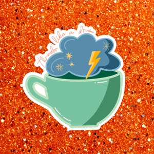 May include: A sticker featuring a teal teacup with a cloud and lightning bolt design. The cloud is blue with yellow stars and a yellow lightning bolt. The text "thunder like a drum" is written above the teacup.