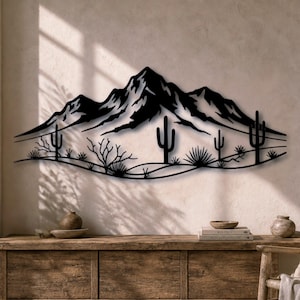 Può includere: Un'opera d'arte da parete in metallo nero che raffigura un paesaggio desertico con una grande catena montuosa sullo sfondo e diversi cactus saguaro e arbusti del deserto in primo piano. Il design è una silhouette continua con linee nette.