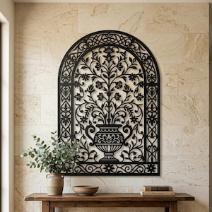 Può includere: Un'opera d'arte da parete in metallo nero caratterizzata da una cornice ad arco con un intricato design tagliato al laser che raffigura un'urna centrale riempita di rami e foglie floreali stilizzati. Il motivo simmetrico include volute.